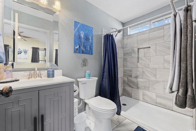 full bath featuring toilet, ceiling fan, vanity, and a tile shower