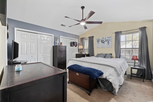 bedroom with vaulted ceiling, multiple windows, visible vents, and two closets