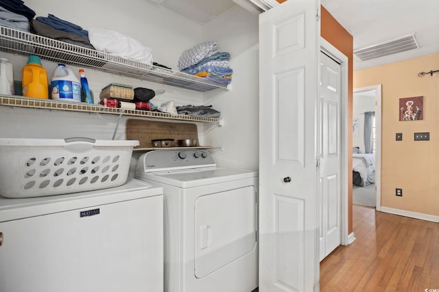 washroom featuring visible vents, washer and clothes dryer, light wood finished floors, baseboards, and laundry area