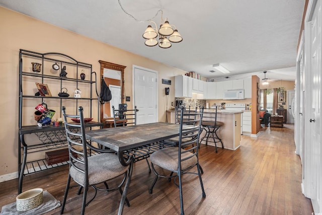 dining space with baseboards, light wood-style flooring, and ceiling fan with notable chandelier