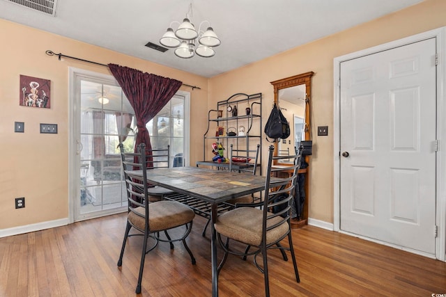 dining area featuring visible vents, baseboards, an inviting chandelier, and wood finished floors