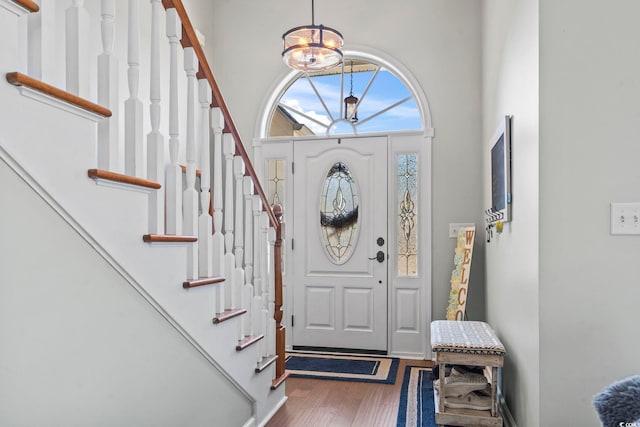 entryway with dark wood finished floors, an inviting chandelier, and stairway