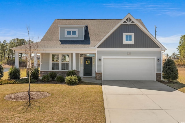 craftsman-style house featuring a front yard, a porch, concrete driveway, a garage, and stone siding