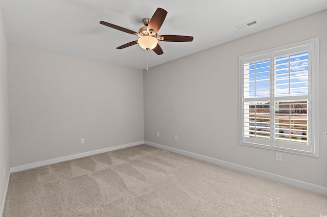 carpeted empty room with visible vents, a ceiling fan, and baseboards