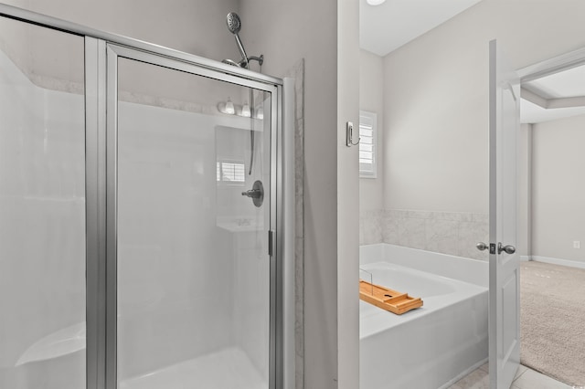 bathroom with baseboards, a garden tub, and a shower stall