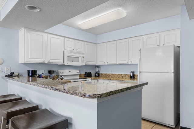 2201 S Ocean Blvd Unit 1707, Myrtle Beach, SC 29577 - kitchen with white appliances, a peninsula, a textured ceiling, a breakfast bar, and white cabinetry