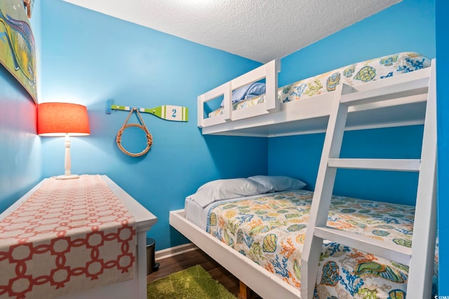 bedroom with baseboards, a textured ceiling, and wood finished floors