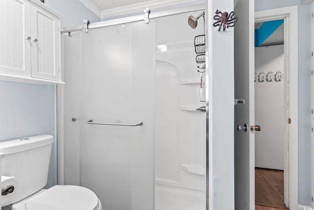 bathroom with a shower stall, toilet, and wood finished floors