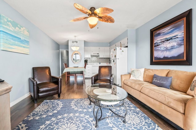 living area featuring a ceiling fan, baseboards, and dark wood-style flooring