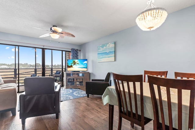 dining space featuring ceiling fan with notable chandelier, wood finished floors, and a textured ceiling