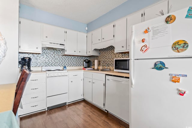 kitchen with tasteful backsplash, under cabinet range hood, dark wood finished floors, white appliances, and a sink