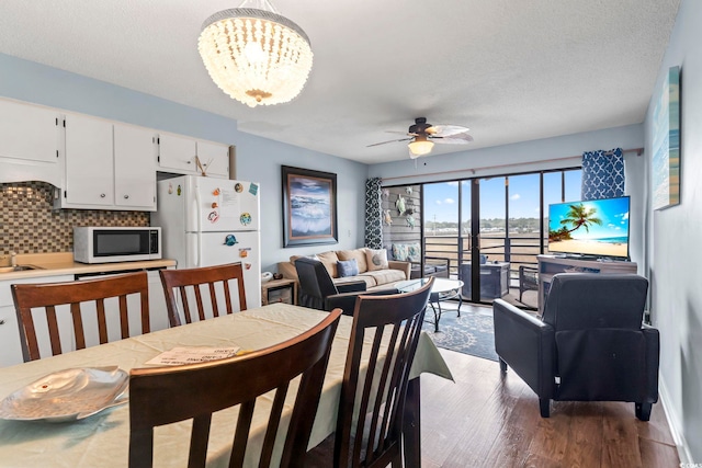 dining space with ceiling fan with notable chandelier, a textured ceiling, and wood finished floors