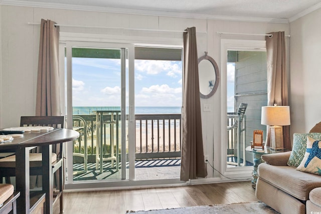 doorway to outside with a wealth of natural light, crown molding, hardwood / wood-style floors, and a water view