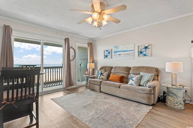 living room featuring a textured ceiling, ornamental molding, and ceiling fan