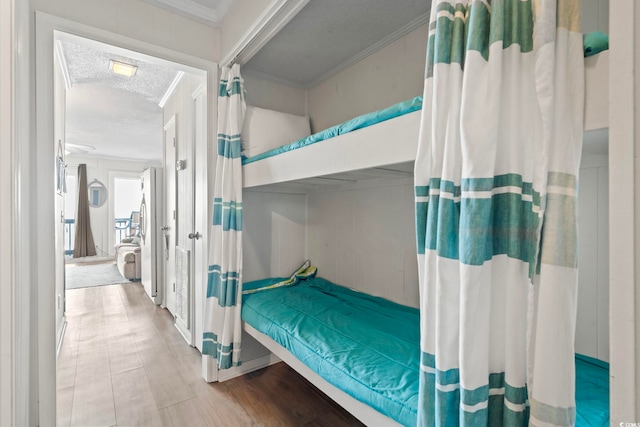 bedroom featuring wood finished floors, a textured ceiling, and crown molding
