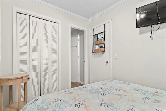 bedroom with wood finished floors, a closet, and crown molding