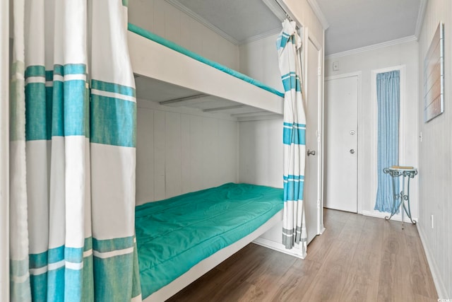 bedroom with baseboards, crown molding, and wood finished floors