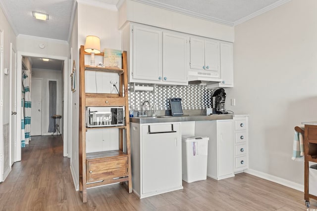 kitchen with light wood-type flooring, a textured ceiling, and under cabinet range hood