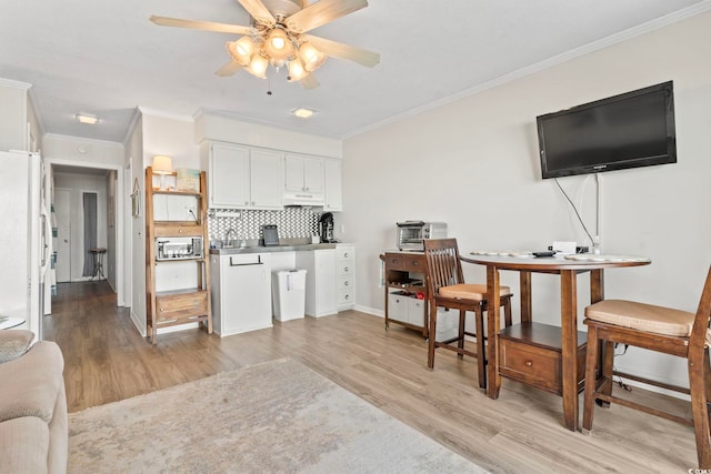 kitchen featuring stainless steel microwave, light wood-type flooring, and crown molding