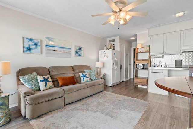 living room featuring wood finished floors, ceiling fan, and crown molding