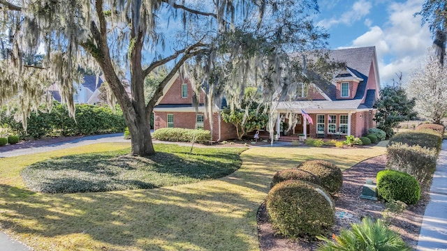 view of front facade featuring a front yard, a porch, and brick siding