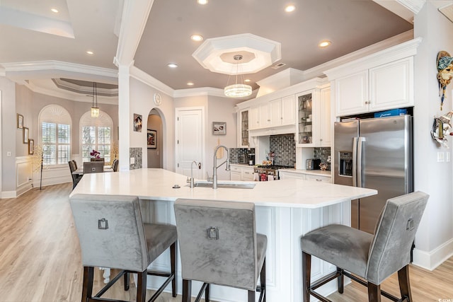 kitchen with a breakfast bar, a tray ceiling, arched walkways, stainless steel appliances, and a sink