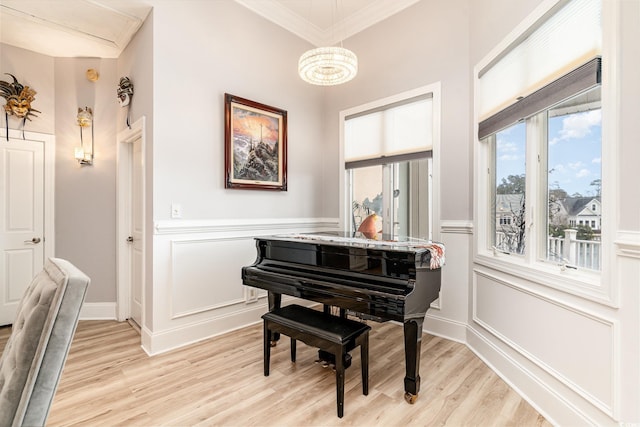 sitting room with light wood-style flooring, crown molding, and a decorative wall