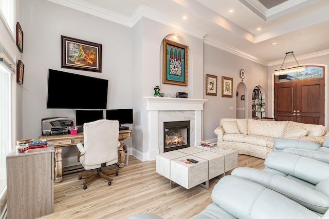 living room featuring light wood-type flooring, recessed lighting, arched walkways, a fireplace, and crown molding