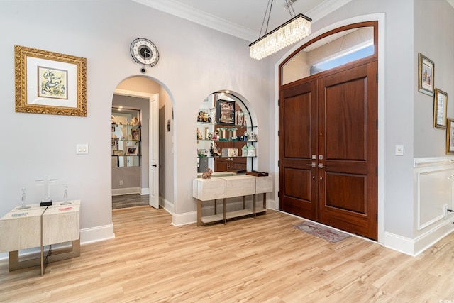 entryway featuring light wood-style flooring, crown molding, and baseboards