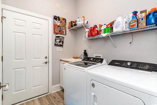 laundry area featuring washing machine and clothes dryer, cabinet space, light wood finished floors, and a sink