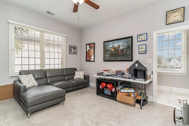 carpeted living area with visible vents, baseboards, a healthy amount of sunlight, and ceiling fan