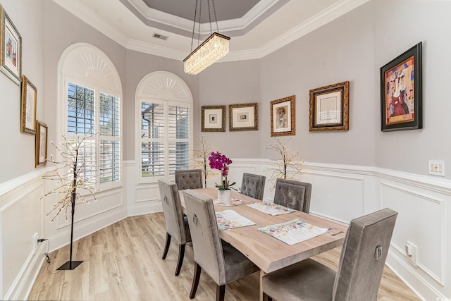 dining area featuring light wood finished floors, visible vents, crown molding, and a tray ceiling