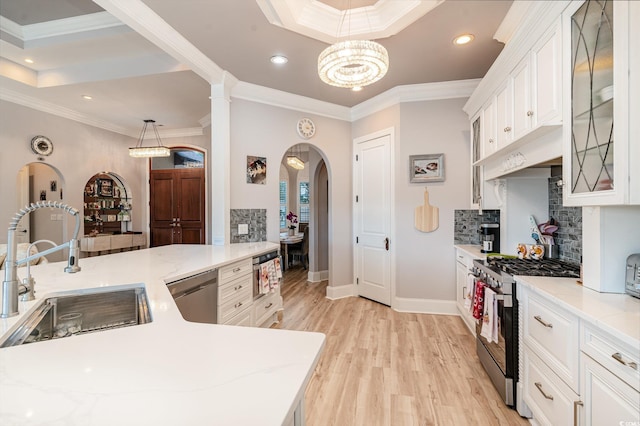 kitchen featuring light wood-style flooring, a sink, white cabinetry, appliances with stainless steel finishes, and decorative backsplash