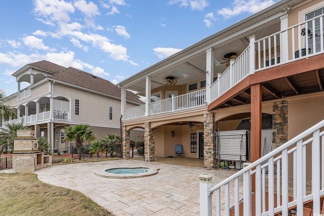 view of patio featuring a balcony, an outdoor hot tub, and ceiling fan