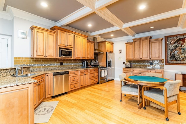 kitchen with light stone countertops, light wood finished floors, a sink, appliances with stainless steel finishes, and wall chimney range hood