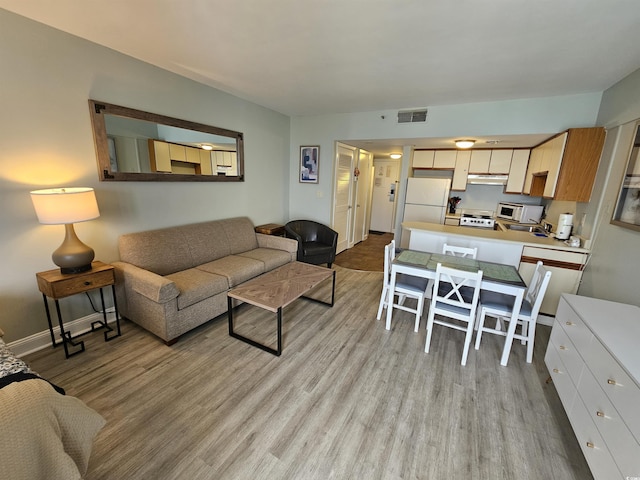 living area with baseboards, visible vents, and light wood finished floors