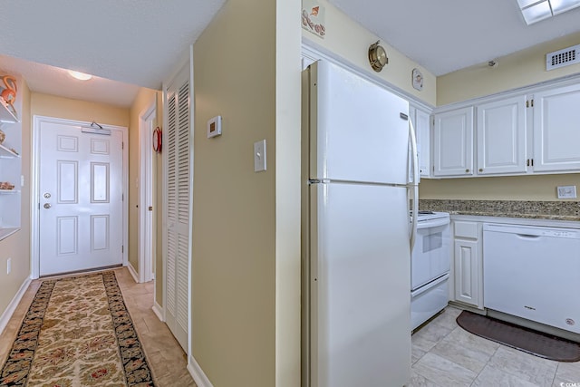 kitchen featuring visible vents, a textured ceiling, white cabinetry, white appliances, and baseboards