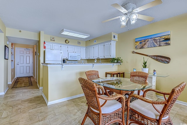 dining room featuring visible vents, a ceiling fan, baseboards, and a textured ceiling