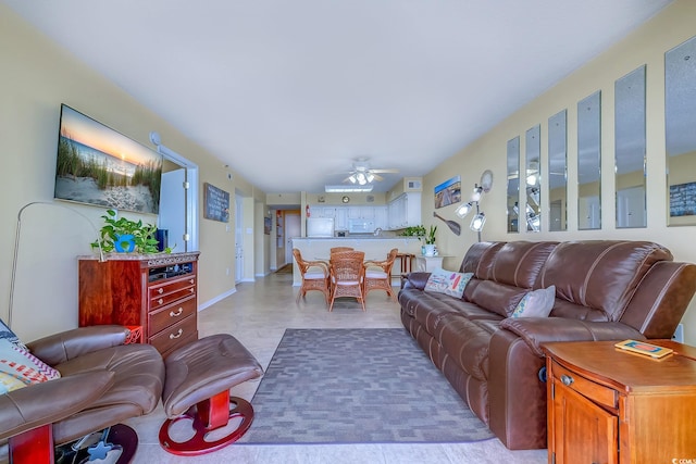 living area with baseboards and ceiling fan