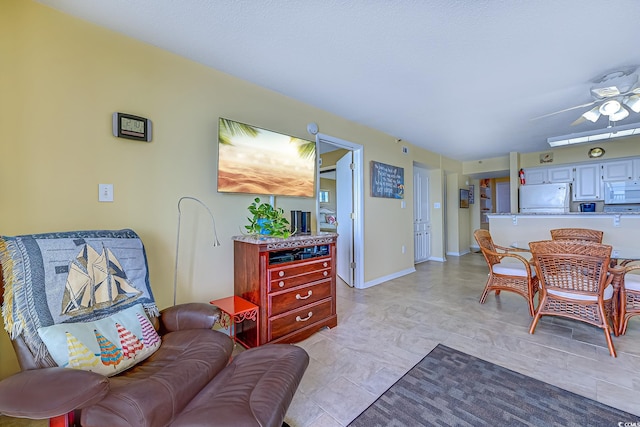 living room with baseboards and ceiling fan