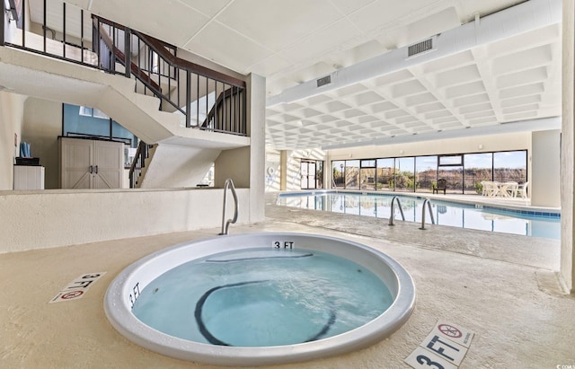 pool featuring an indoor hot tub, stairs, and a patio area