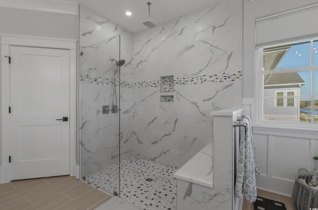 bathroom featuring wood finish floors, a marble finish shower, and plenty of natural light