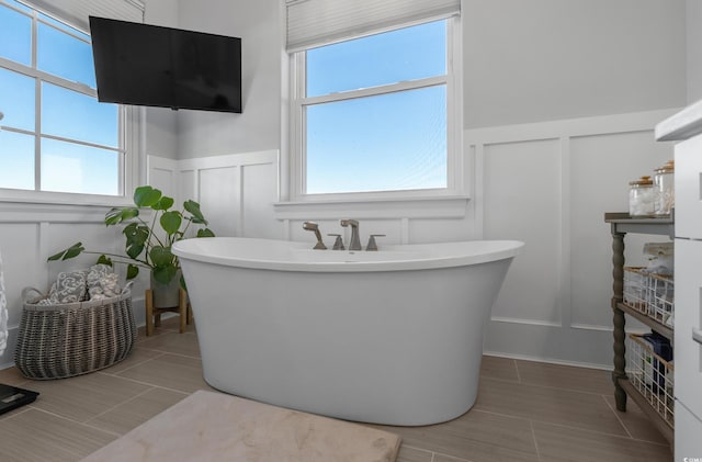 full bathroom featuring a wainscoted wall, a freestanding bath, and a decorative wall