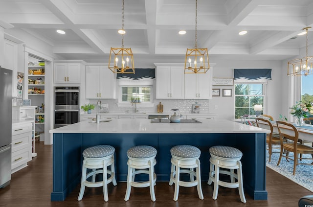 kitchen featuring a sink, a spacious island, appliances with stainless steel finishes, and a chandelier