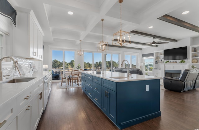 kitchen with a sink, blue cabinets, a fireplace, and ceiling fan with notable chandelier