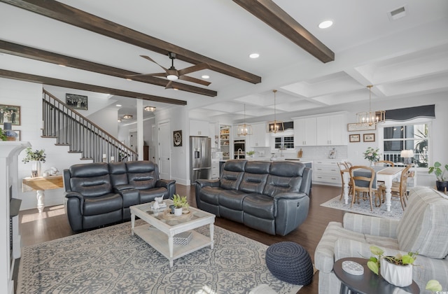 living room with stairway, visible vents, beam ceiling, dark wood-style flooring, and ceiling fan with notable chandelier