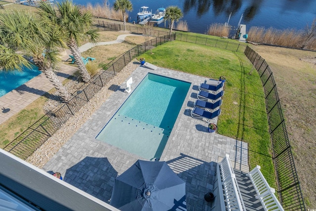 community pool featuring a yard, a water view, and a fenced backyard