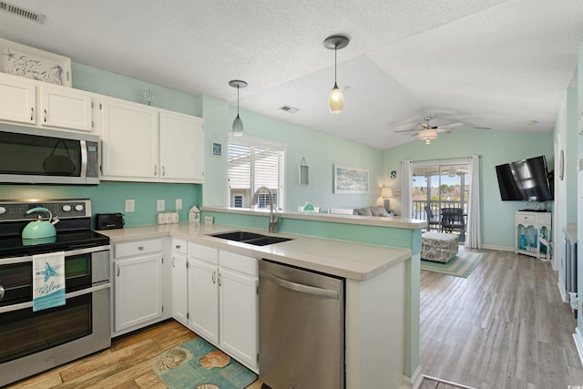 kitchen featuring visible vents, a sink, open floor plan, stainless steel appliances, and a peninsula