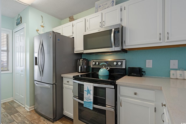 kitchen featuring light countertops, white cabinets, tasteful backsplash, and stainless steel appliances