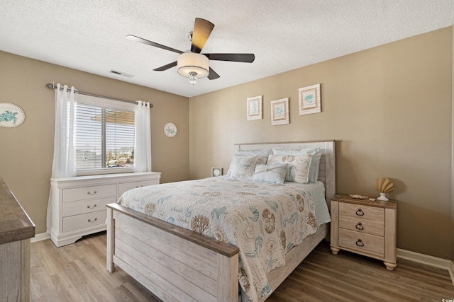 bedroom with baseboards, visible vents, a textured ceiling, and light wood-style floors